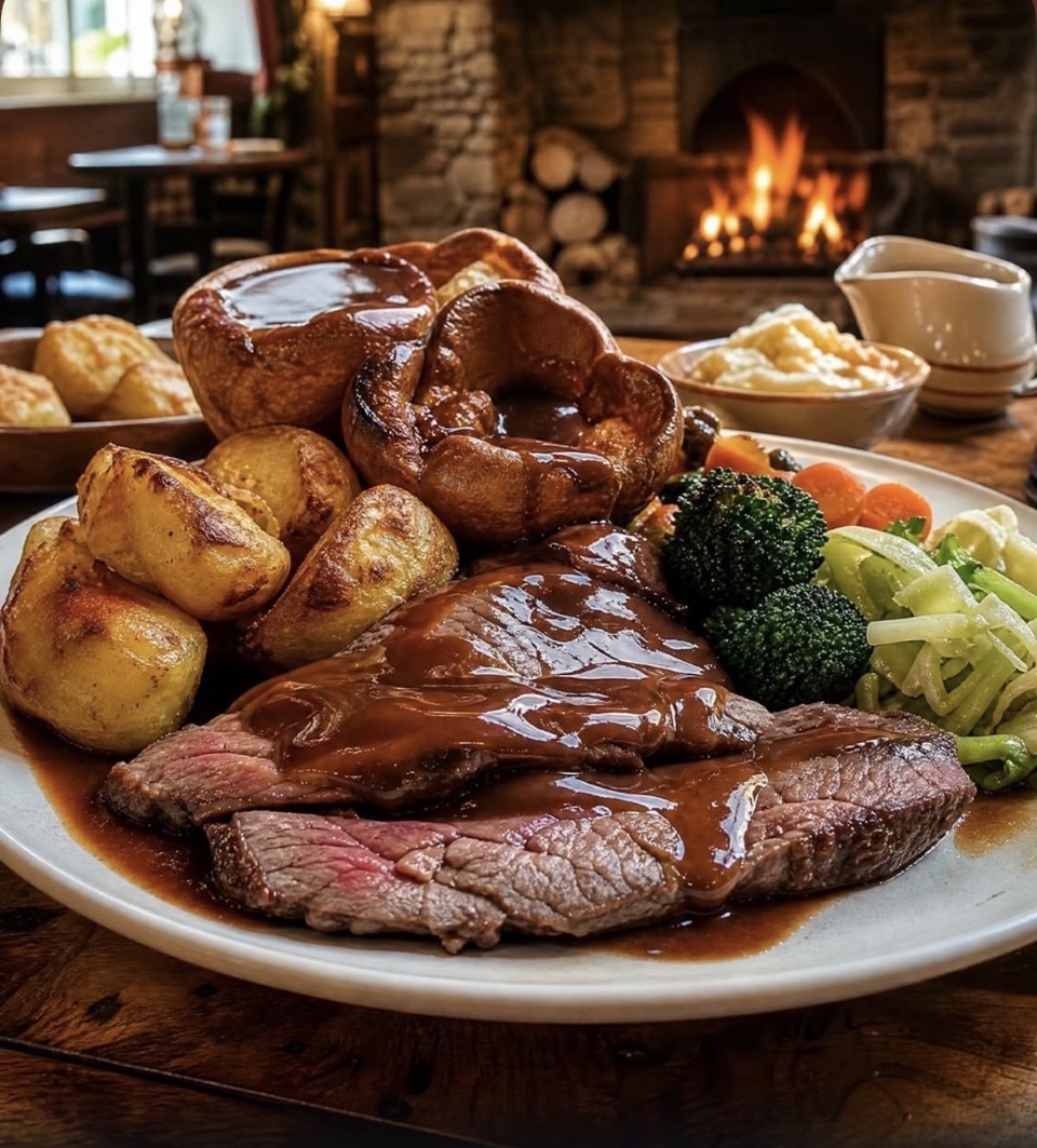 A proper British Sunday roast dinner with beef, roast potatoes, Yorkshire puddings, vegetables and gravy